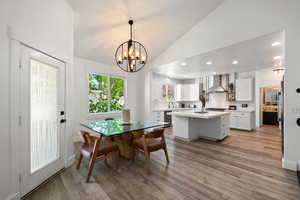 Dining space with lofted ceiling, a textured ceiling, light wood-type flooring, recessed lighting, and a chandelier