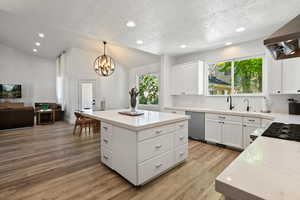 Kitchen featuring open floor plan, white cabinetry, a center island, a textured ceiling, and recessed lighting