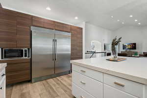 Kitchen with appliances with stainless steel finishes, a textured ceiling, light wood finished floors, light stone countertops, and recessed lighting