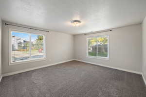 Empty room with dark carpet and a textured ceiling