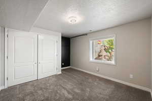 Unfurnished bedroom with carpet, a textured ceiling, and a closet