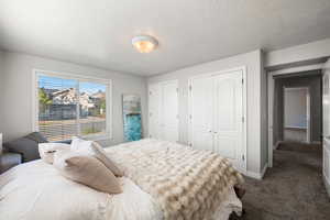 Bedroom featuring two closets, carpet flooring, and a textured ceiling
