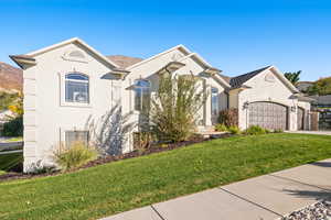 French provincial home featuring a front lawn, stucco siding, an attached garage, and driveway
