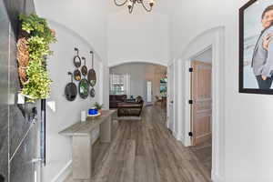 Hallway featuring high vaulted ceiling, wood finished floors, arched walkways, and a chandelier