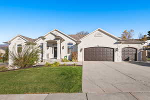 View of front of house featuring stucco siding, a front yard, concrete driveway, and a garage