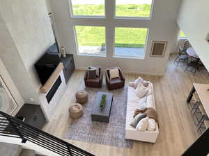 Living room featuring light wood-style floors, a glass covered fireplace, and a high ceiling
