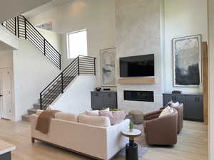 Living area featuring light wood finished floors, a tile fireplace, a high ceiling, and stairway