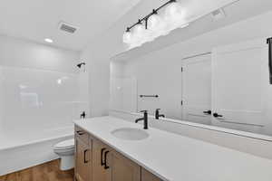 Full bath with vanity, shower / bathtub combination, and dark wood-type flooring