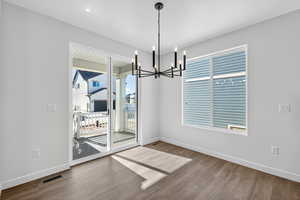 Unfurnished dining area with a chandelier and wood finished floors