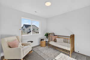 Bedroom featuring a nursery area and carpet flooring