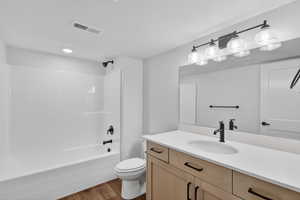 Full bathroom with vanity, shower / washtub combination, and dark wood-type flooring