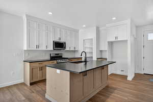 Kitchen featuring dark countertops, decorative backsplash, appliances with stainless steel finishes, dark wood-style floors, and recessed lighting