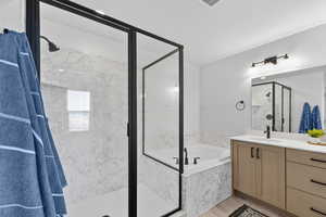 Bathroom with a garden tub, a marble finish shower, and vanity
