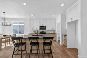Kitchen with dark countertops, an island with sink, appliances with stainless steel finishes, recessed lighting, and a chandelier