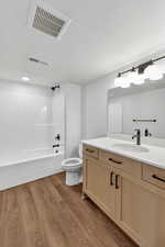 Bathroom featuring vanity, shower / bath combination, light wood-style flooring, and a textured ceiling