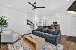 Living area with dark wood-type flooring, recessed lighting, stairway, ceiling fan, and a chandelier