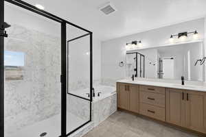 Bathroom featuring a garden tub, double vanity, and a marble finish shower