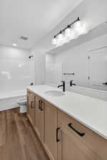 Bathroom with vanity, shower / tub combination, and dark wood-type flooring