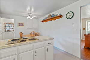 Kitchen featuring light countertops, white cabinetry, stainless steel electric stovetop, and a ceiling fan