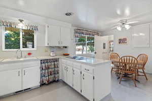 Kitchen featuring a peninsula, light countertops, white cabinets, tasteful backsplash, and ceiling fan