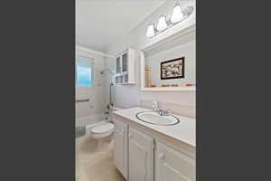 Bathroom with vanity, tub / shower combination, and light tile patterned flooring