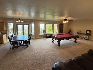 Rec room featuring a textured ceiling, light colored carpet, pool table, and a chandelier