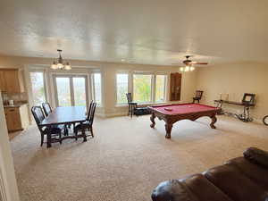 Recreation room featuring light carpet, billiards table, a textured ceiling, a chandelier, and a ceiling fan