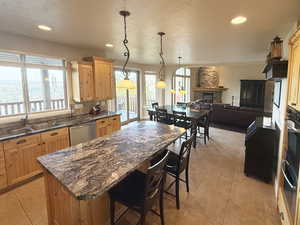 Kitchen with a kitchen island, dark stone counters, light tile patterned flooring, a breakfast bar area, and recessed lighting