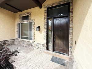 Property entrance featuring stone siding and a patio area
