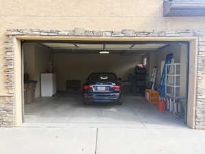Garage with freestanding refrigerator and concrete driveway