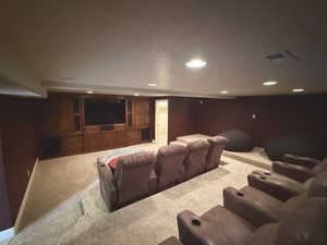 Cinema room with light carpet and a textured ceiling