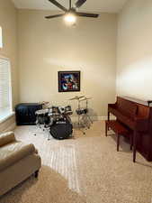 Living area featuring light colored carpet, a towering ceiling, and ceiling fan