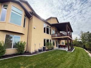 Rear view of property featuring a patio area, a lawn, stucco siding, and an outdoor living space