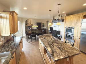 Kitchen featuring a kitchen island, dark stone counters, light tile patterned floors, a chandelier, and recessed lighting