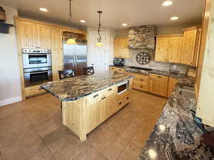 Kitchen with dark stone counters, stainless steel appliances, backsplash, a breakfast bar area, and recessed lighting
