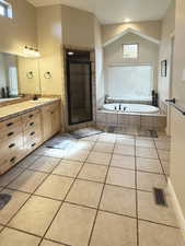 Full bath featuring a garden tub, vanity, light tile patterned floors, a stall shower, and vaulted ceiling