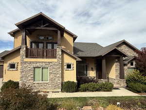 Craftsman-style house featuring stone siding, stucco siding, a balcony, and roof with shingles