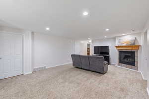 Living area 2 with light carpet, a gas log tile fireplace, recessed lighting, and basement entrance to the backyard