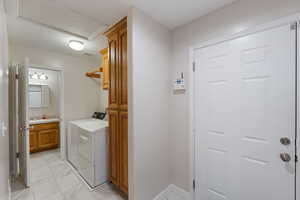 Laundry area with light marble finish flooring, cabinet space, and washing machine and clothes dryer