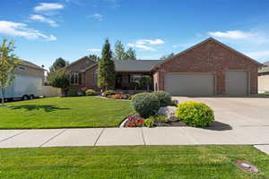Ranch-style home with a front yard, brick siding, a garage, and driveway fitting 4 vehicles