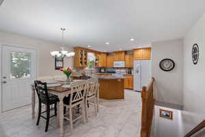 Dining area & kitchen with light marble finish floors, a chandelier, and recessed lighting