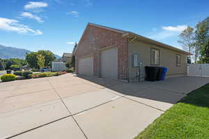 View of side of home with brick siding, Transfer Switch for Emergency Power in power outages, 4 car garage, RV pad fitting 2 additional cars, a trailer, or a boat, and a mountain view, a gate, and concrete driveway