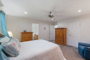 Primary Bedroom featuring light carpet, recessed lighting, walk-in closet extending all along north wall, and a ceiling fan