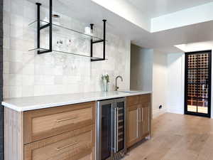 Indoor wet bar featuring wine cooler and mosaic tile, and wine closet