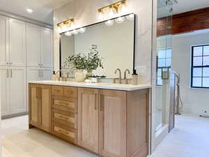 Primary bathroom with double vanity, a steam shower, soaking tub, custom tile work, and built-in closet system