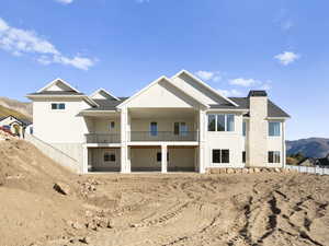Back of house featuring a mountain view, a chimney, a balcony, and a patio