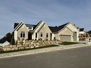 View of front of property with a standing seam roof, a metal roof, stone siding, and driveway