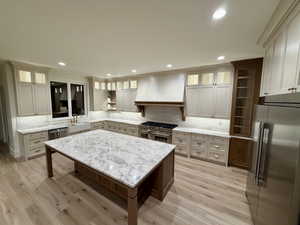 Kitchen featuring premium appliances, backsplash, recessed lighting, light stone countertops, and a center island