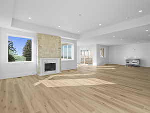 Lliving room with light wood finished floors, recessed lighting, and a stone fireplace