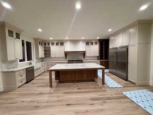 Kitchen featuring stainless steel appliances, a center island, a kitchen bar, glass insert cabinets, and tasteful backsplash
